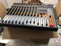 Mixer unit on table showing top-panel controls, faders and ports