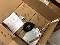 Open cardboard box containing multiple Yuurta LED gimbal pot light boxes and one light removed showing black trim and attached junction box