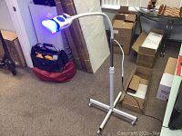 Full view of the assembled teeth whitening machine on stand with blue LED mouthpiece light on.