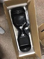 Top-down view of black hoverboard in cardboard box with foam padding