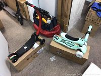 Red U-Kiss scooter and teal plastic scooter displayed on boxes