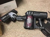 Photo of a black and grey cordless handheld vacuum cleaner labeled 'Cyclone Enhanced' and 'RoomieTEC'.
