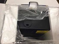 Top view of black ultrasonic humidifier in box with plastic wrap and foam padding.