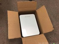 Mini refrigerator in open brown cardboard box showing closed front door with 'Mini Refrigerator' text.