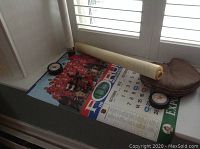 Leather catcher's glove, hockey pucks, small hockey player action figures, and Montreal Canadiens 1972-1973 calendar on a windowsill.