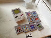 Photo of Nintendo Game Boy console and 8 game cartridges laid out on surface.