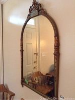 Front view of large decorative mirror with ornate carved arch and side accents.