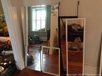 View of two large mirrors; one black framed and one white framed leaning on wall