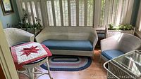 Overview of white wicker seating set including loveseat, armchair and small table