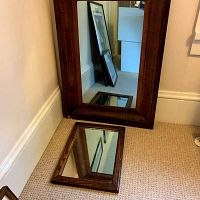 Both mirrors placed on carpet, large mahogany veneer mirror standing and smaller oak framed mirror laying down