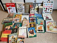 Books arranged on floor showing cover details including Keith Haring, The Way Things Work, My First Encyclopedia, Velveteen Rabbit, and others.