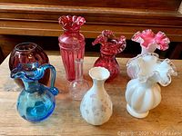Group of 8 decorative glass vases in various colors and styles including Fenton milk glass and depression era glass.