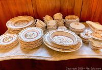 Full set of Spode Buttercup dishes arranged on marble surface showcasing large plates, smaller plates, tea cups and saucers, serving platters, bowls, and accessories.