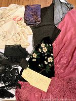 Various textile pieces laid out including embroidered silk doilies, black lace trims, and the purple silk shawl.