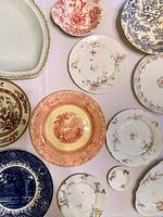 Overview of various plates and dishes showing floral and scenic designs in pink, blue, and multicolor patterns.
