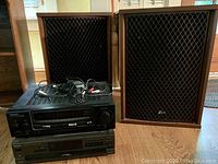 Two Sansui floor-standing speakers flanking Kenwood receiver and Technics CD player on hardwood floor