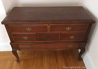 Front view of lowboy cedar chest showing four top false front drawers with brass handles and one bottom dovetail drawer with wooden knob. Lowboy style with curved legs.
