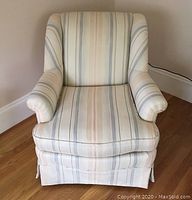 Front view of swivel rocker armchair showing pale blue and peach striped upholstery on cream background with cushioned seat and skirted base.