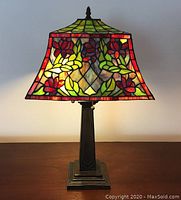 Full view of the Tiffany-style lamp showing stained glass shade and deco metal base.