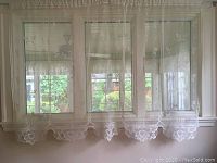 Full view of six lace curtain panels hanging on window, showing floral scalloped edges and delicate lace fabric.