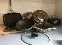 Overview of non-stick cookware set and maple cutting board on kitchen counter