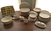 Overview of full set laid out on table showing plates, bowls, cups, saucers and storage cases