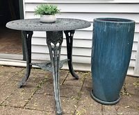 Photo showing the wrought iron look garden table next to the tall blue glazed planter with the small plastic fern on the table.