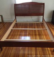 Full view of bed frame showing slatted headboard, side rails, and footboard on wood floor.