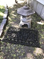 Stone pagoda with heavy rubber decorative mat placed on ground outdoors, showing size and condition
