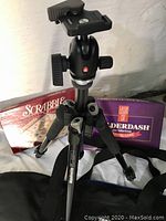 Manfrotto tripod with ball head mount displayed along with Balderdash and Scrabble board games.