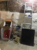 View showing six-foot aluminum ladder, three-foot aluminum ladder, various painting supplies, and storage container with extension cords