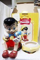 Full assembled view of Pinocchio cookie jar with matching lid and original yellow box in background with Disney Pinocchio labelling.
