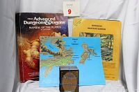 Photo showing the Manual Of The Planes hardcover book with distinct cover art, Dungeon Masters Screen in yellow, the Forgotten Realms map laid flat, and a stack of Magic The Gathering cards.