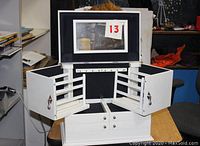 Front view showing the top lid open with mirror, plus the side earring racks extended on both sides revealing their structure and capacity.