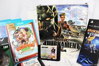 Photo showing boxed Atari Unreal Tournament 2004, Nintendo Wii game cases Donkey Kong Country Tropical Freeze, Disney Infinity Editions 2.0 and 3.0, and vintage SEGA Genesis game cartridges.