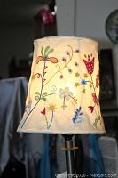 Close-up of the 9-inch floral embroidered lampshade showing colorful flower and vine pattern on cream fabric.