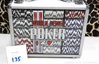 Front view of poker chip and card set inside metal and acrylic lockable case showing 15 stacks of chips and 4 sealed decks of cards