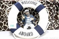 Front view of sailor skipper statue inside 'Welcome Aboard' buoy ring.