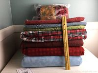 Stack of flannel fabric yardage pieces in multiple colors with a ruler for scale