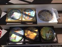 Overview photo showing all five collector plates, two in yellow bordered boxes (Zhou Huimin) and three Knowles Ancient Elements plates by Georgia Lambert, some boxes damaged.