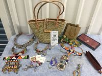 Full view of the lot spread out on table showing woven bag, seed bead chokers and bracelets, Kazuri pottery, and small storage cases.