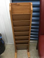 Front view of wooden vertical magazine rack showing multiple shelves for magazines