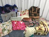 Photo of 10 bags and wallet arranged showing colors and styles including Vera Bradley signature patterns and prints