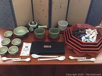 Photo showing entire tea set spread out with teapot, cups, saucers, trays, chopsticks in case, spoons, and chopstick rests.