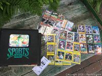 Photo of black binder labeled 'Sports Cards' and cards spread out on surface showing various baseball and basketball trading cards.