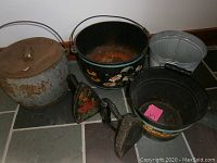 Full overview of the collection showing three pots, metal bucket, and two flat irons on tile floor