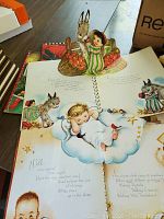 Pop-up children's book open showing detailed colorful illustrations and text with a child sleeping on a cloud and animals around