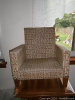 Front view of the vintage children's rocking chair showing the patterned fabric upholstery and wooden rocker base.