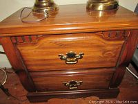 Front angled close-up of the top drawer and brass handle, showing wood grain and minor scuffs.