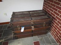 Full front angle of vintage wooden trunk showing metal reinforcements and latch